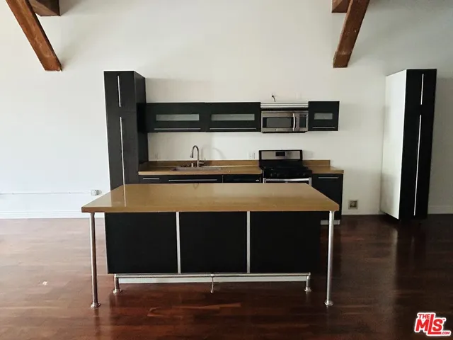 a kitchen with stainless steel appliances a refrigerator and wooden floor