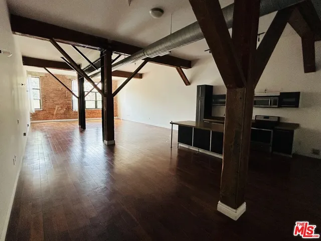 a view of an empty room with wooden floor and windows