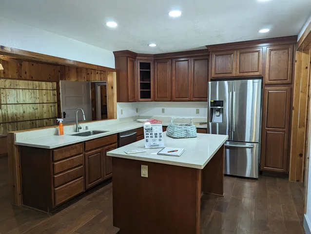 a kitchen with kitchen island granite countertop a sink stove and refrigerator