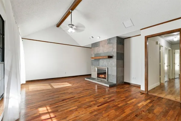 a view of a livingroom with wooden floor a fireplace and window