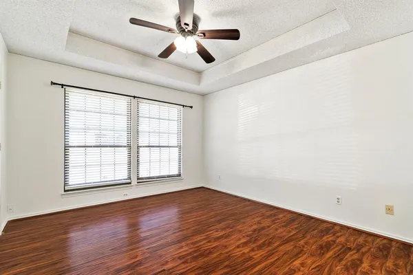 an empty room with wooden floor fan and windows