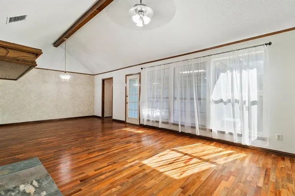 a view of an empty room with a window and wooden floor