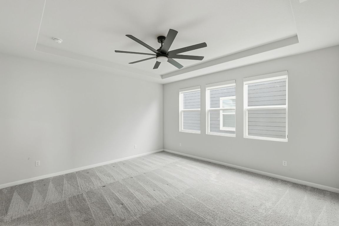 1941 Winston Way Leander, TX 78641 - Photo 15 of 28 Carpeted empty room featuring a tray ceiling and ceiling fan