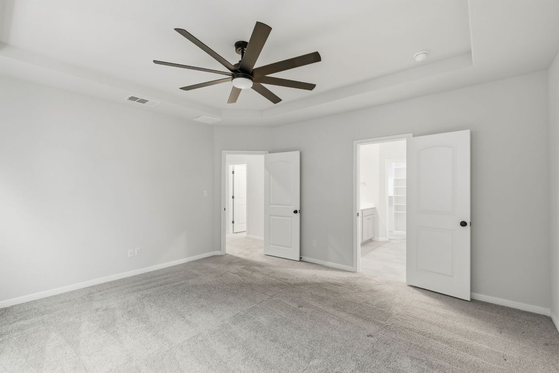 1941 Winston Way Leander, TX 78641 - Photo 16 of 28 Unfurnished bedroom with a raised ceiling, light colored carpet, a ceiling fan, and connected bathroom