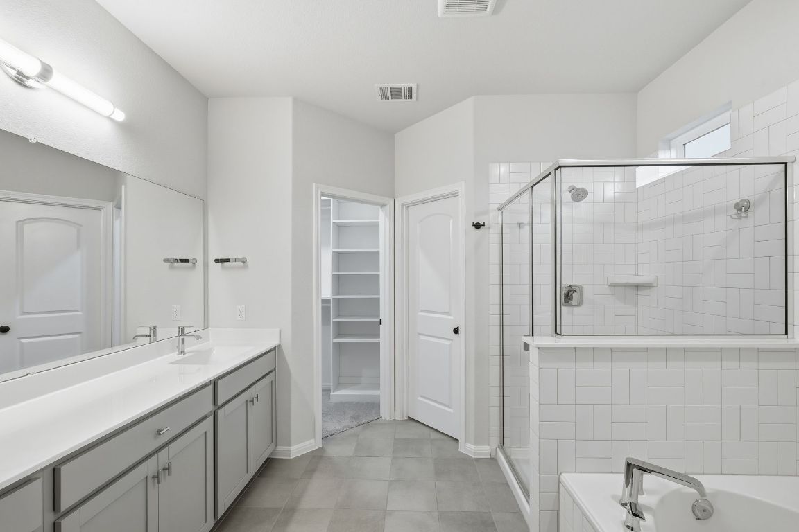 1941 Winston Way Leander, TX 78641 - Photo 17 of 28 Full bathroom featuring a garden tub, vanity, a walk in closet, and a shower stall