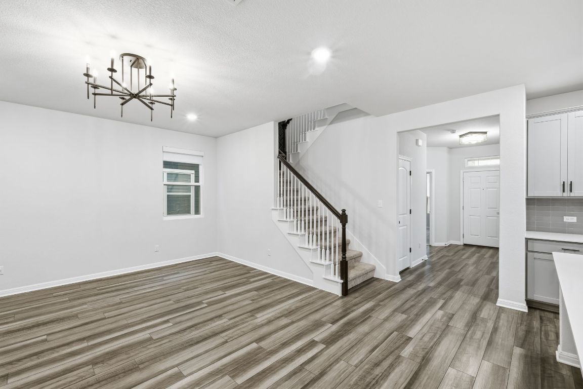 1941 Winston Way Leander, TX 78641 - Photo 4 of 28 Unfurnished living room featuring stairs, dark wood finished floors, a chandelier, and recessed lighting