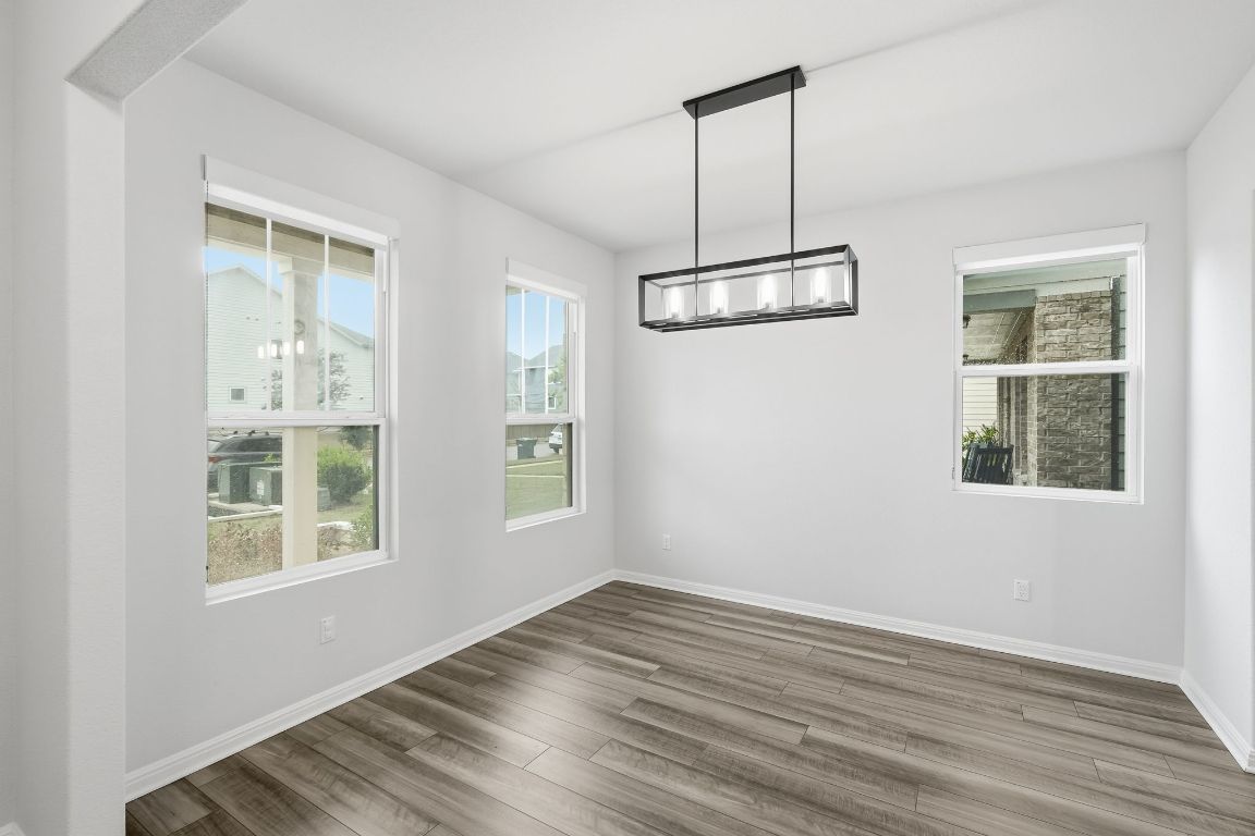 1941 Winston Way Leander, TX 78641 - Photo 7 of 28 Unfurnished dining area featuring wood finished floors and a chandelier
