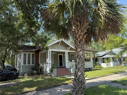 a front view of a house with garden and trees