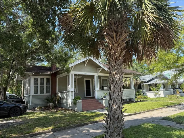 a front view of a house with garden and trees