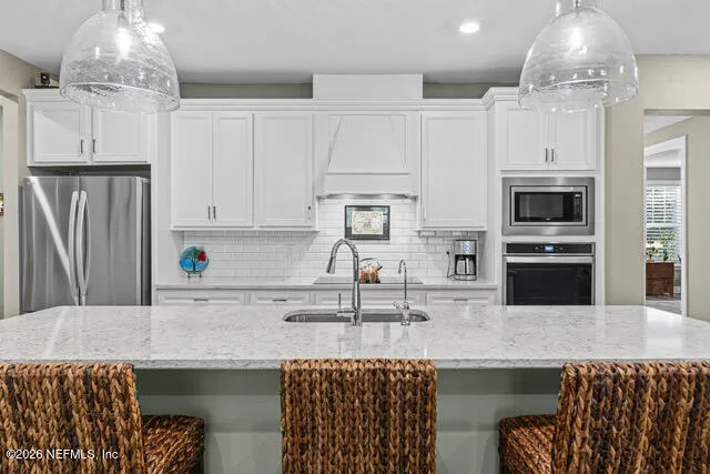 a large white kitchen with a large island oven a stove a chimney a sink and a large window