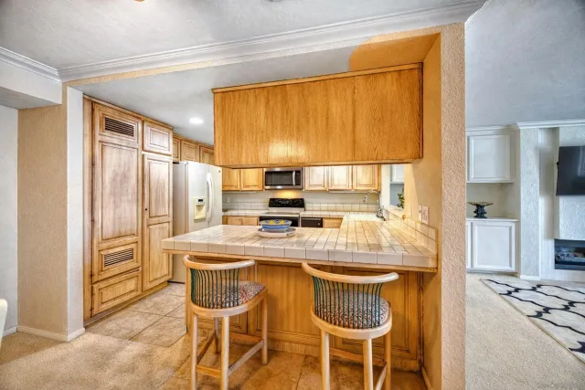 a kitchen with stainless steel appliances granite countertop a stove a refrigerator a sink a dining table and chairs with wooden floor