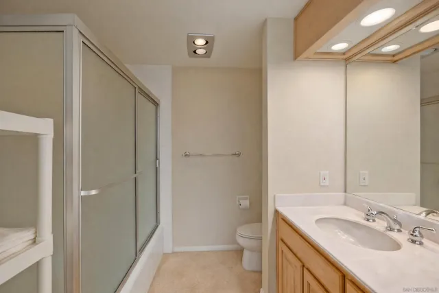 a bathroom with a granite countertop sink a mirror and a toilet