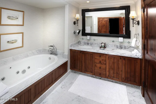 a bathroom with a tub a double vanity sink and mirror