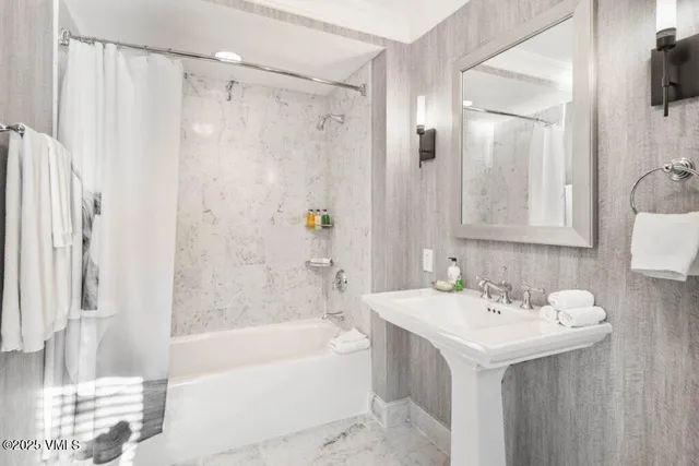 a bathroom with a sink a mirror a bathtub and shower