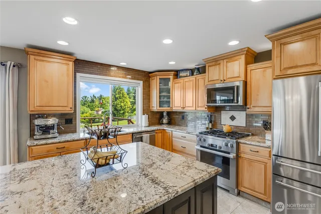 a kitchen with stainless steel appliances granite countertop a stove a sink and a refrigerator