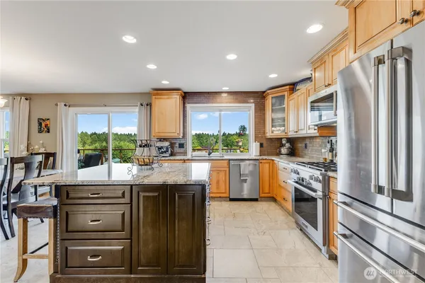 a kitchen with stainless steel appliances granite countertop a stove a sink and a refrigerator