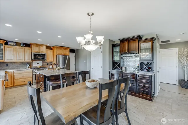 a kitchen with stainless steel appliances granite countertop a table and chairs