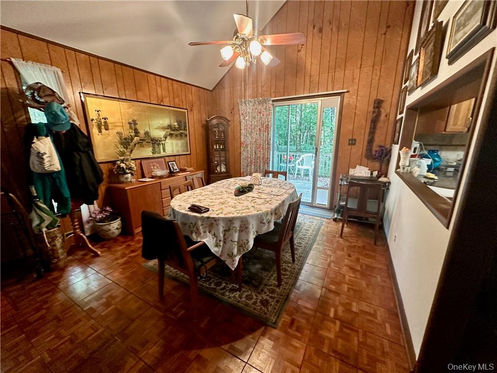 74 Swinging Bridge Estate Road Monticello, NY 12701 - Photo 14 of 36 Dining space with ceiling fan, high vaulted ceiling, dark parquet flooring, and wood walls
