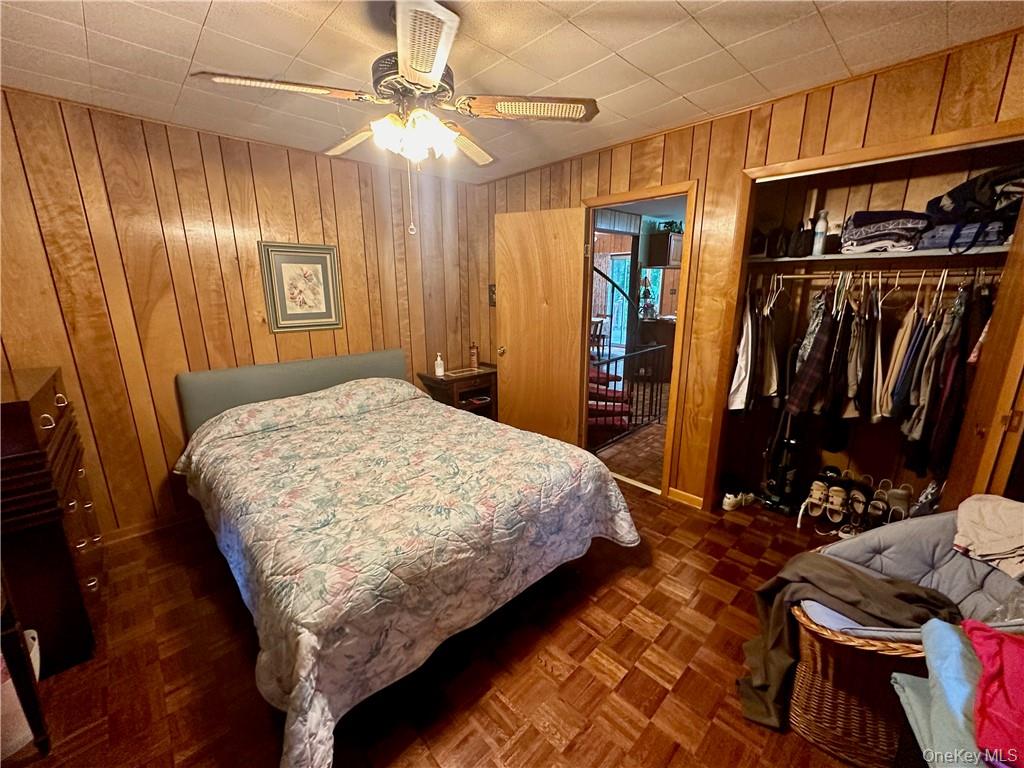 74 Swinging Bridge Estate Road Monticello, NY 12701 - Photo 20 of 36 Bedroom with wood walls, a closet, ceiling fan, and dark parquet floors