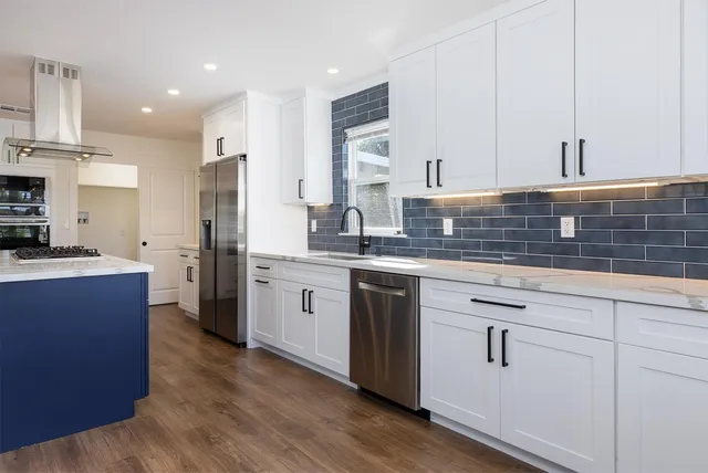 a kitchen with stainless steel appliances granite countertop a sink a stove and wooden floor