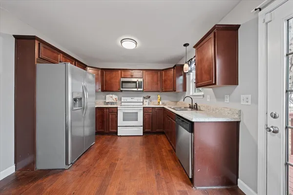 a kitchen with stainless steel appliances granite countertop a refrigerator a sink dishwasher a stove with wooden floor and cabinets