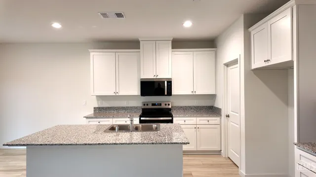 a kitchen with granite countertop white cabinets and black stainless steel appliances