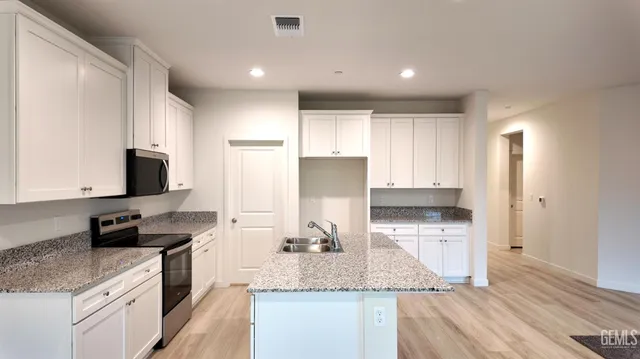 a kitchen with stainless steel appliances granite countertop a sink a stove and a refrigerator