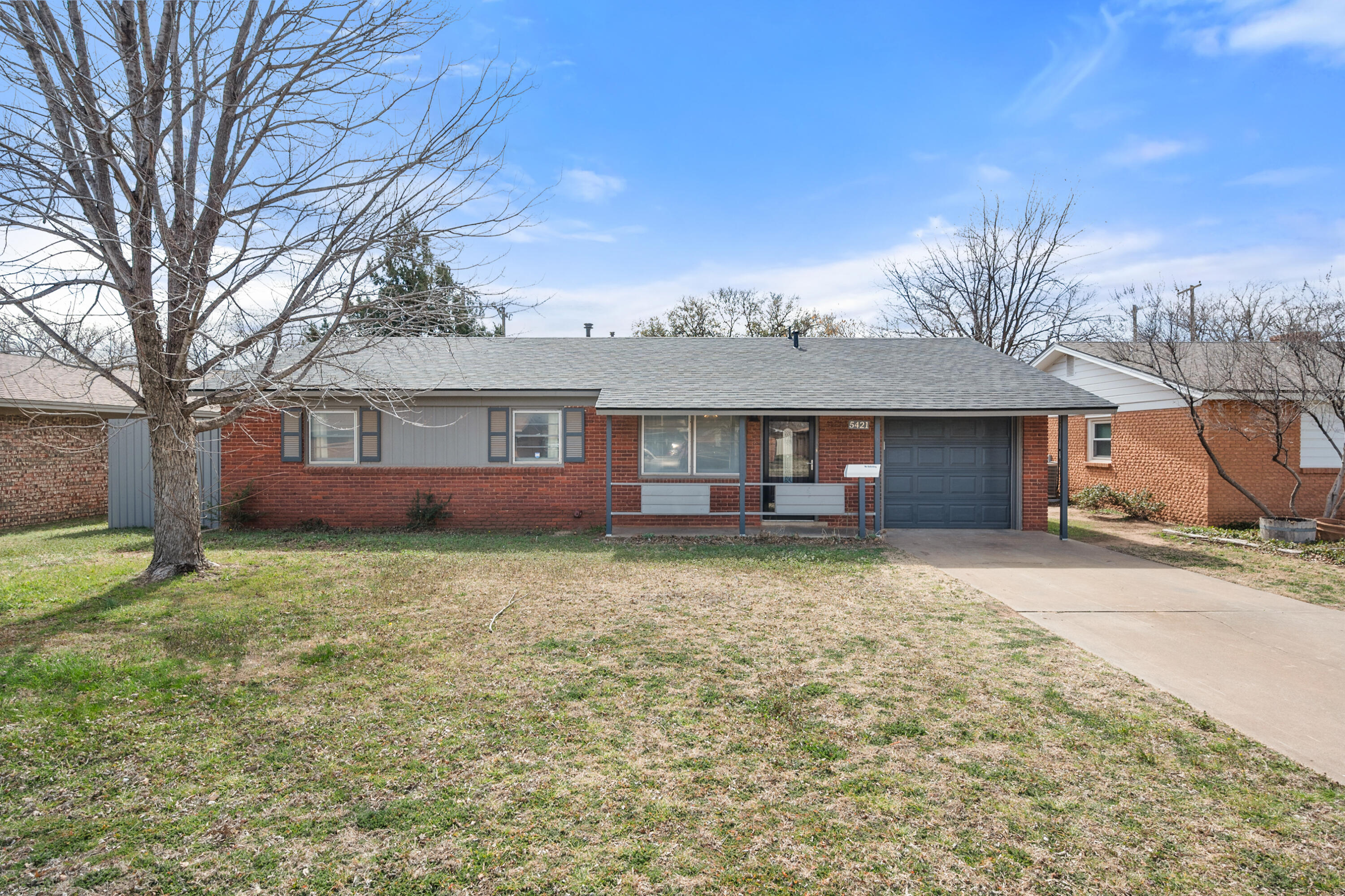 a view of a yard in front of a house with large tree