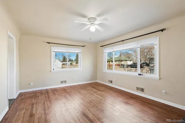 a view of an empty room with wooden floor and a window