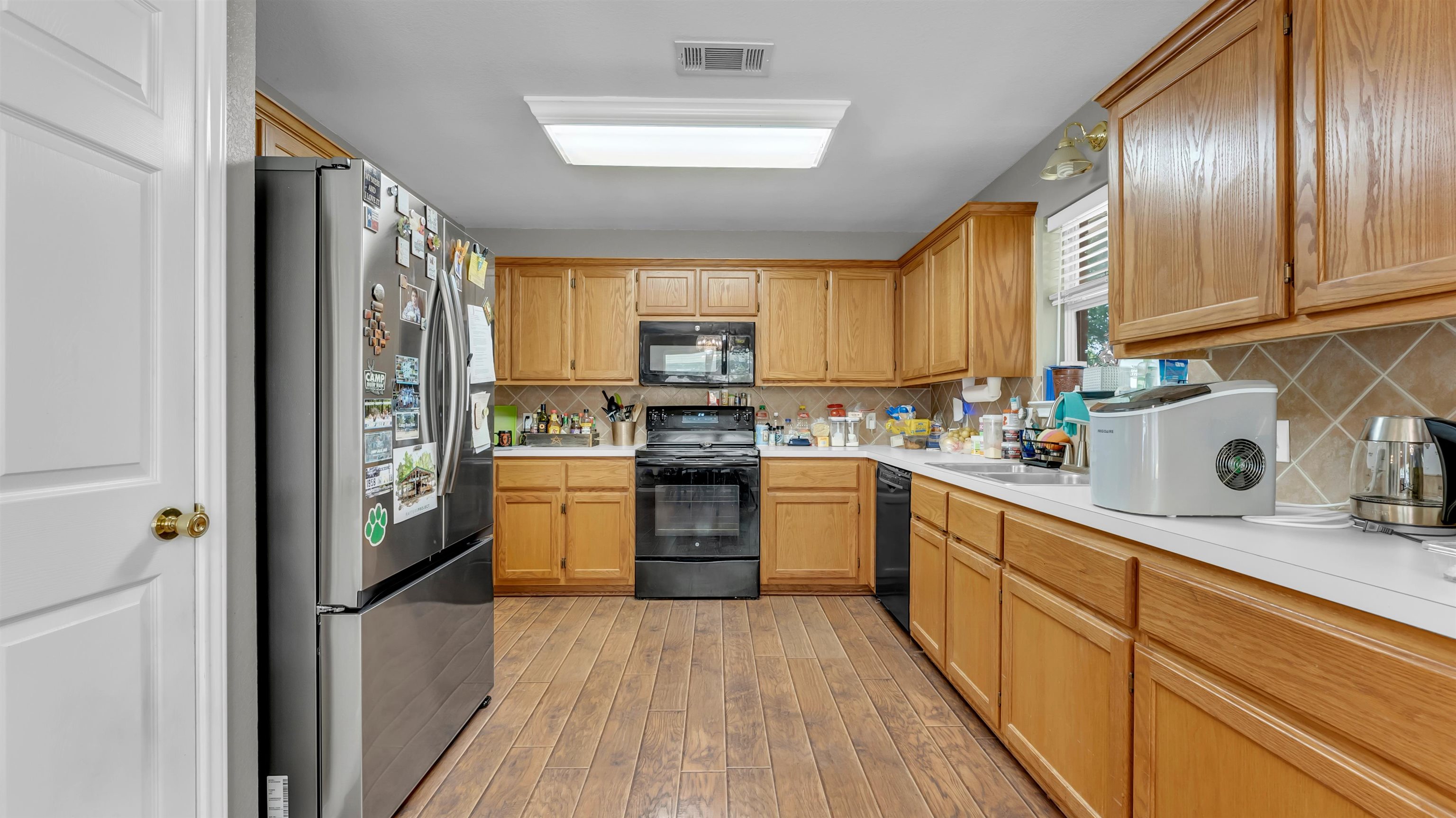 1004 East Johnson Street Burnet, TX 78611 - Photo 7 of 23 a kitchen with stainless steel appliances granite countertop a refrigerator a sink dishwasher a stove and white countertops with wooden floor