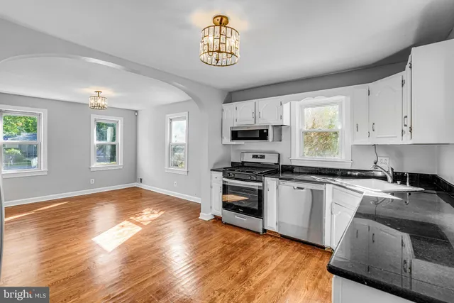 a kitchen with granite countertop a stove a sink dishwasher and a refrigerator with wooden floor