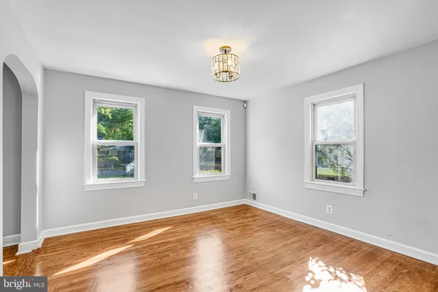a view of an empty room with wooden floor and window