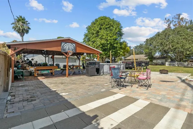 a view of a patio with a table and chairs under an umbrella with a barbeque grill and a fire pit
