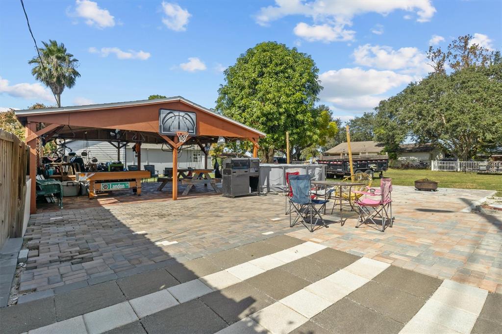 513 5th Street South Dundee, FL 33838 - Photo 24 of 29 a view of a patio with a table and chairs under an umbrella with a barbeque grill and a fire pit