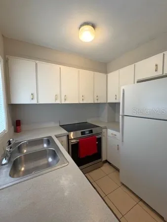 a kitchen with a refrigerator and white cabinets