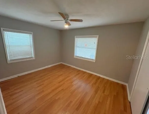 a view of an empty room with wooden floor and a window