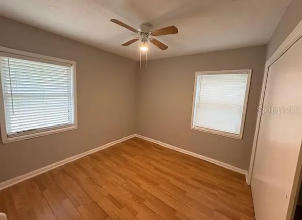 a view of an empty room with wooden floor and a window