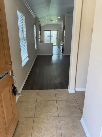 a view of a hallway to an empty room with wooden floor and a window