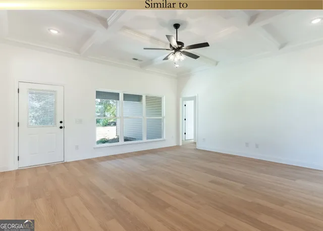 an empty room with wooden floor fan and windows