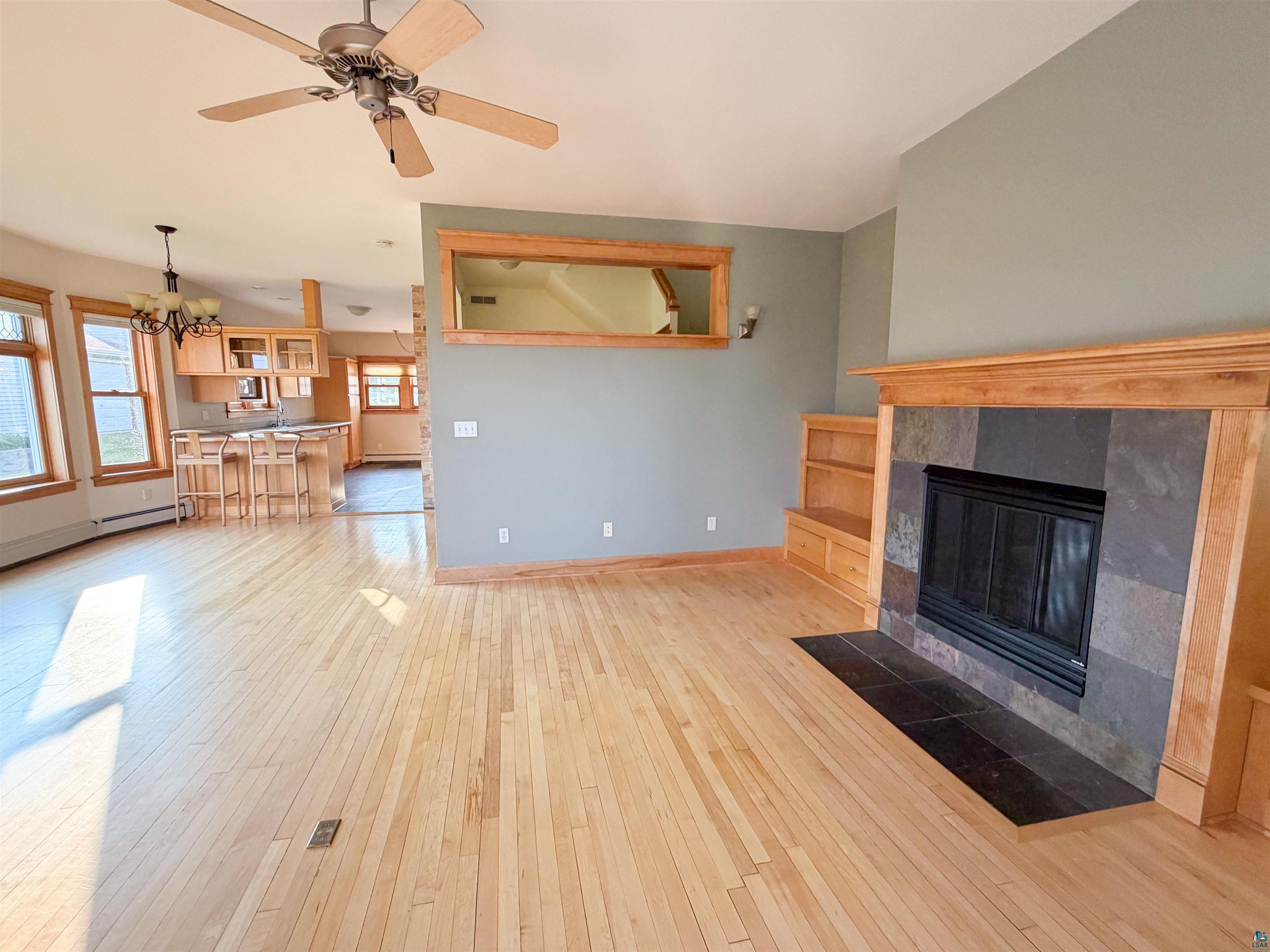 13 West 8th Street Duluth, MN 55806 - Photo 3 of 57 Hardwood flooring spanning the open-concept living area, featuring a fireplace with a stone tile surround and wood mantel