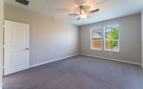 an empty room with windows and fan