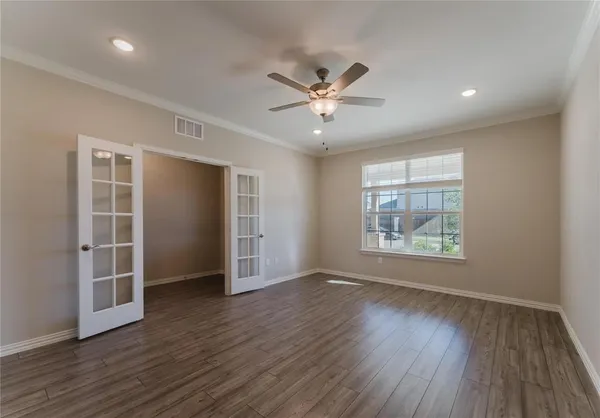 a view of empty room with wooden floor and fan