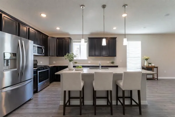 a large kitchen with a table chairs refrigerator and microwave