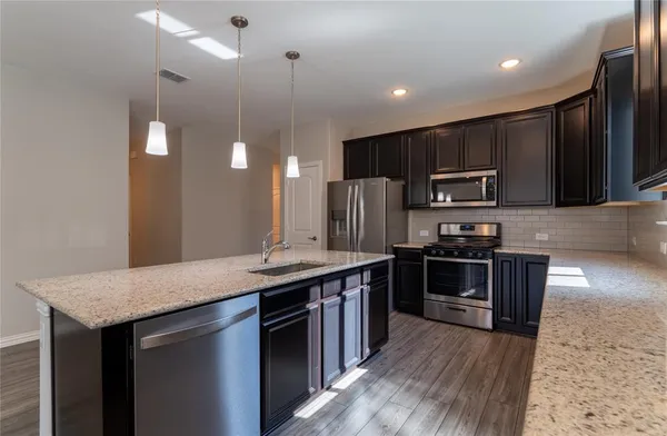 a kitchen with kitchen island granite countertop stainless steel appliances and wooden cabinets