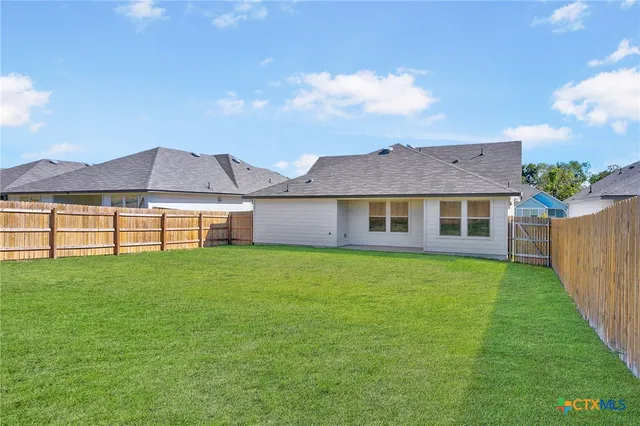a view of a house with a big yard potted plants and large tree