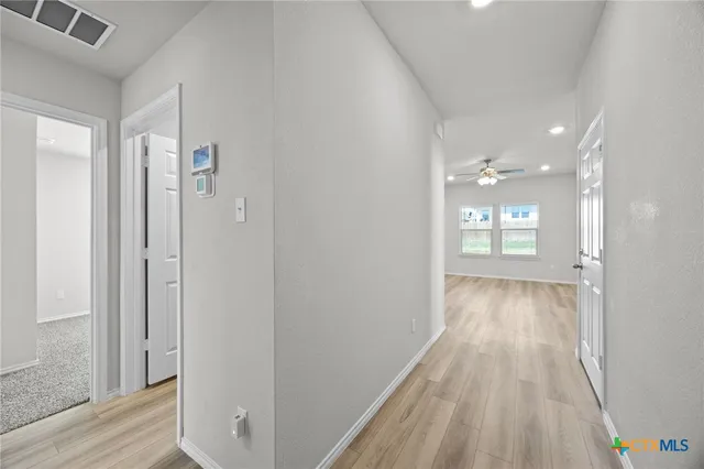 a view of a hallway with wooden floor and a bathroom