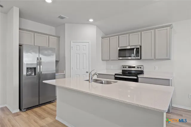 a kitchen with stainless steel appliances a refrigerator a sink a stove a microwave and cabinets