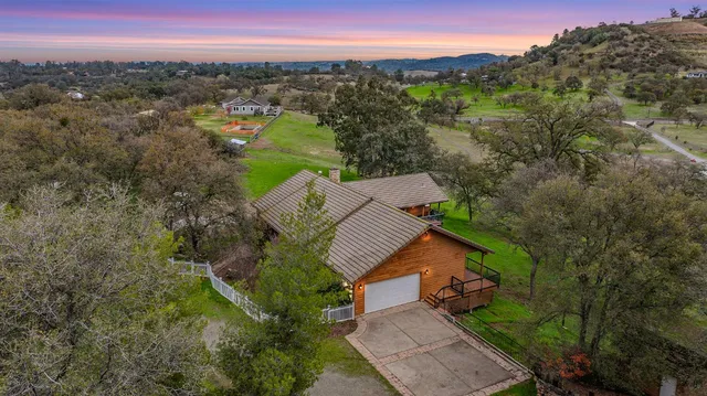 an aerial view of a house with a yard and mountain view in back