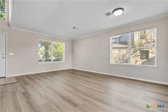 an empty room with wooden floor and windows