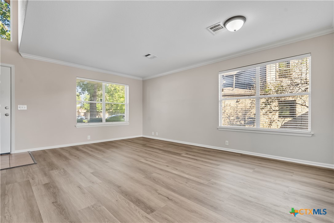 172 Coreopsis Cove Kyle, TX 78640 - Photo 11 of 33 an empty room with wooden floor and windows